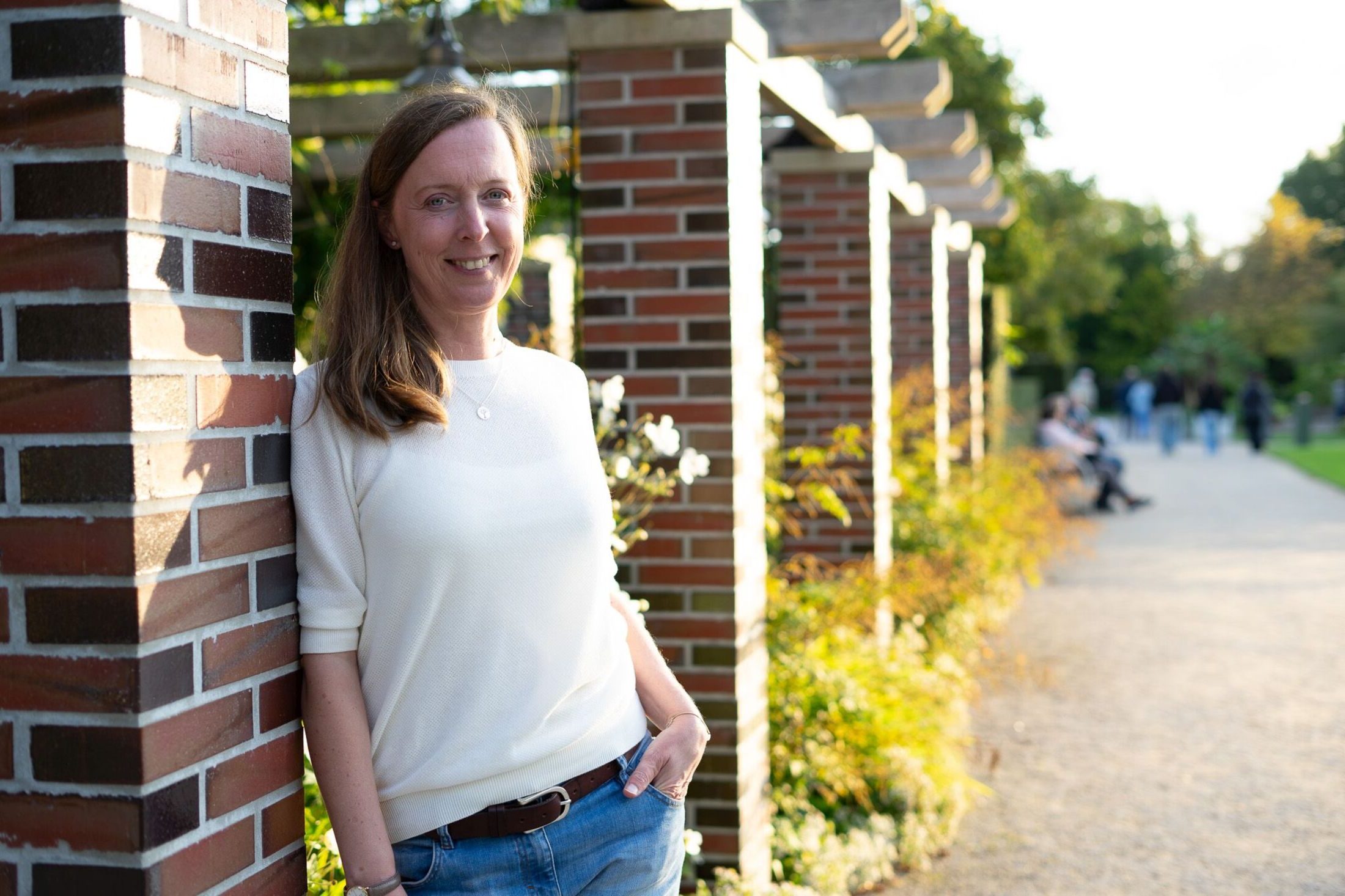 Coach Frauke Lenz entspannt angelehnt an Mauer im Park